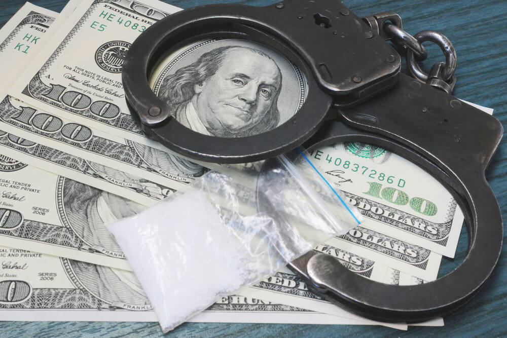 Cuffs and drugs atop money to symbolize drug possession charges
